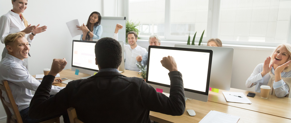 diverse colleagues congratulating black coworker with good result or win